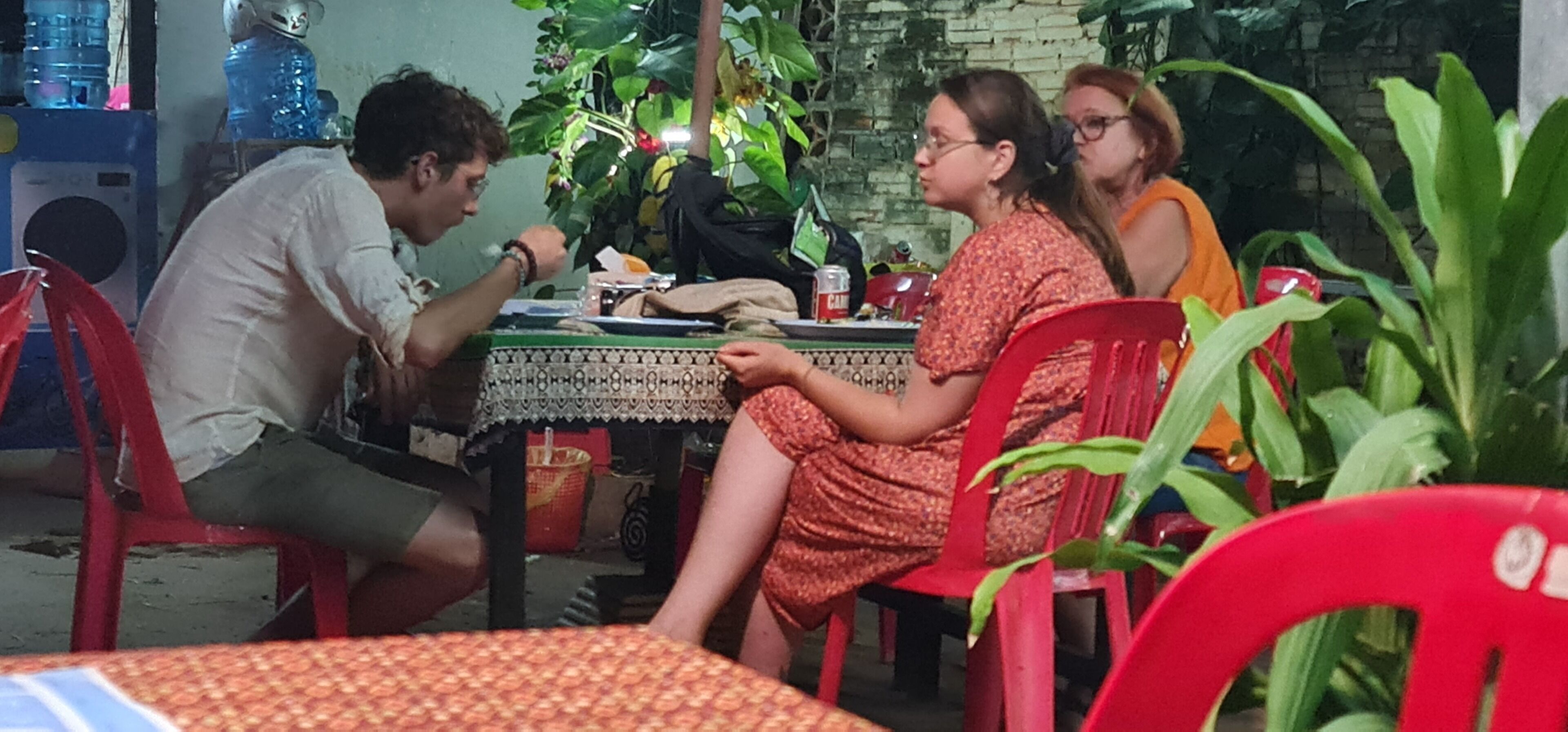 A group of people dining at an outdoor table with a patterned tablecloth.