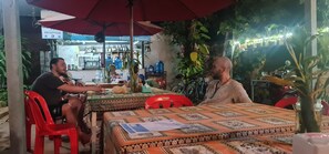 An outdoor dining area with tables and chairs, a reception sign, and a bar in the background. - Relax Resort Angkor Villa (Siem Reap)