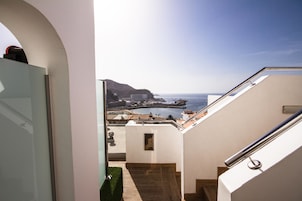 Vista desde un balcón con vistas a la costa, edificios y un cielo despejado.