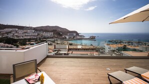 Un balcón con vista a un pueblo costero, una piscina y una playa.