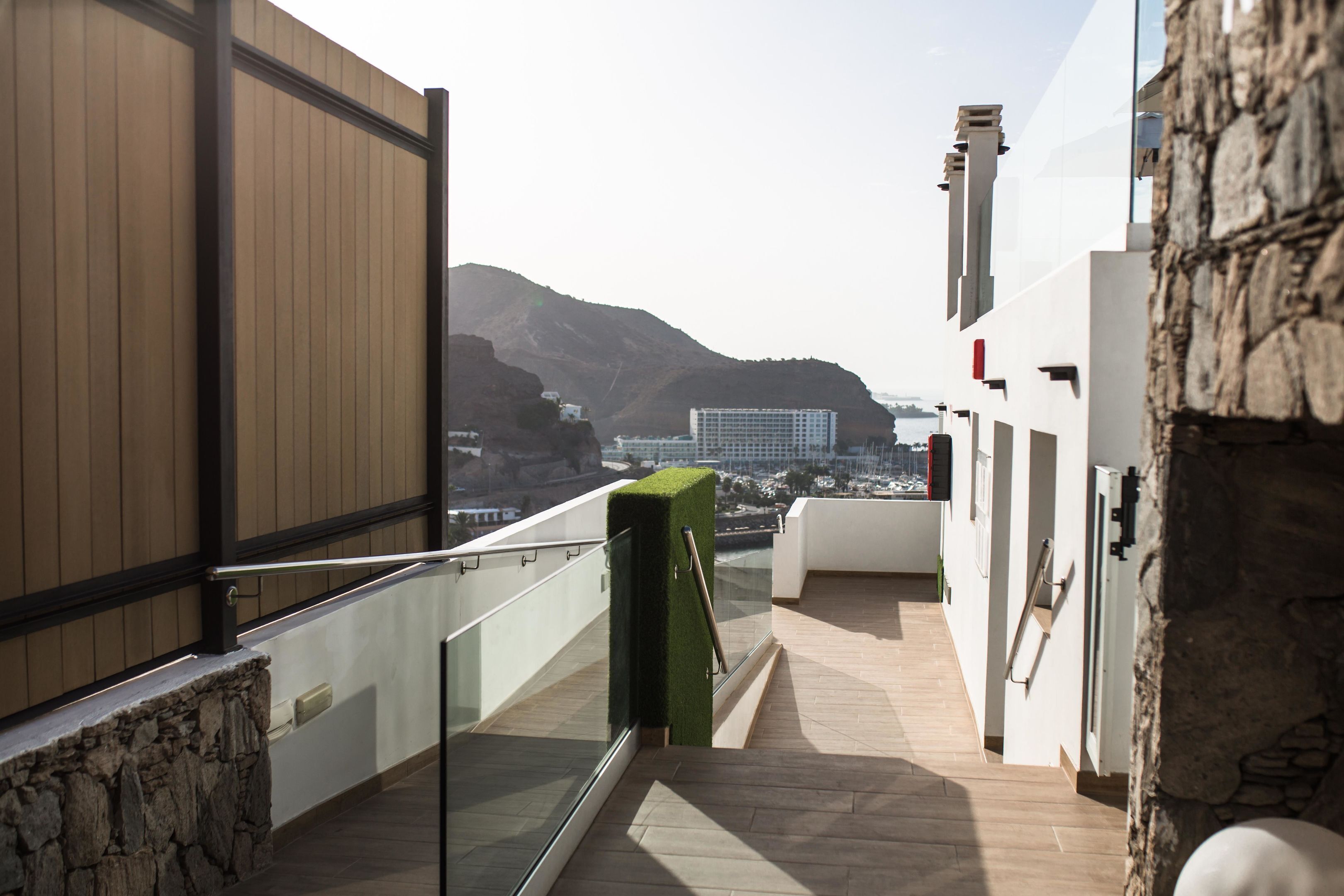 Een modern balkon met stenen muur, houten paneel en glazen hekwerk.