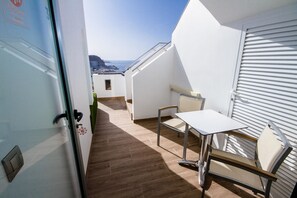Un balcon avec une table et une chaise, une vue sur la ville et une porte dotée d’une poignée.
