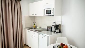 Cafetera o tetera, frigorífico, microondas y placa de cocina