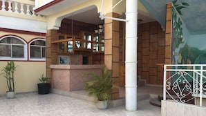 Um hall amplo com piso de azulejos, um balcão de recepção e uma escadaria para um andar superior.