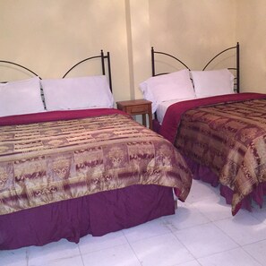 Two beds with headboards, white pillows, and red and brown bedspreads in a room with white tiled flooring. - Paradis Hotel (Petionville)