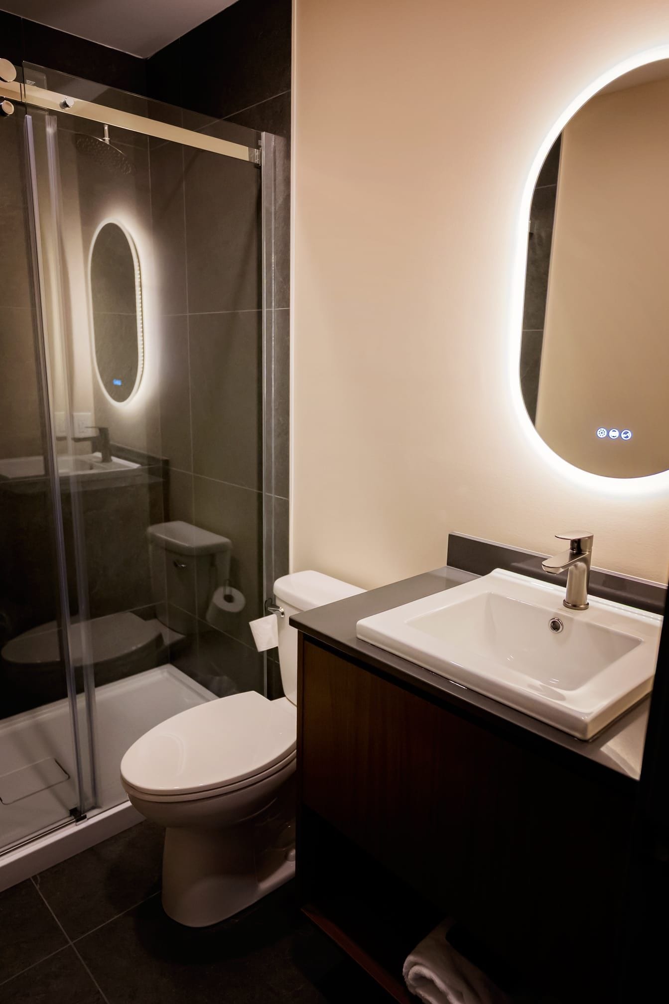Een moderne badkamer met een douchecabine van glas, een toilet en een wastafel met spiegel.