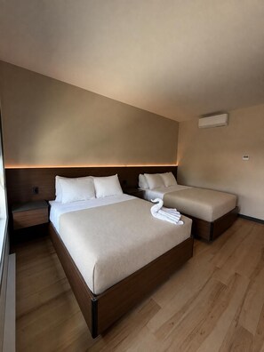 A hotel room with two beds, a nightstand, and a wall-mounted air conditioner. - Motel du Lac Beauchamp (Gatineau)