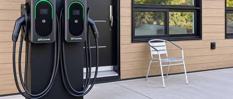Un edificio moderno con dos estaciones de carga para vehículos eléctricos al frente.