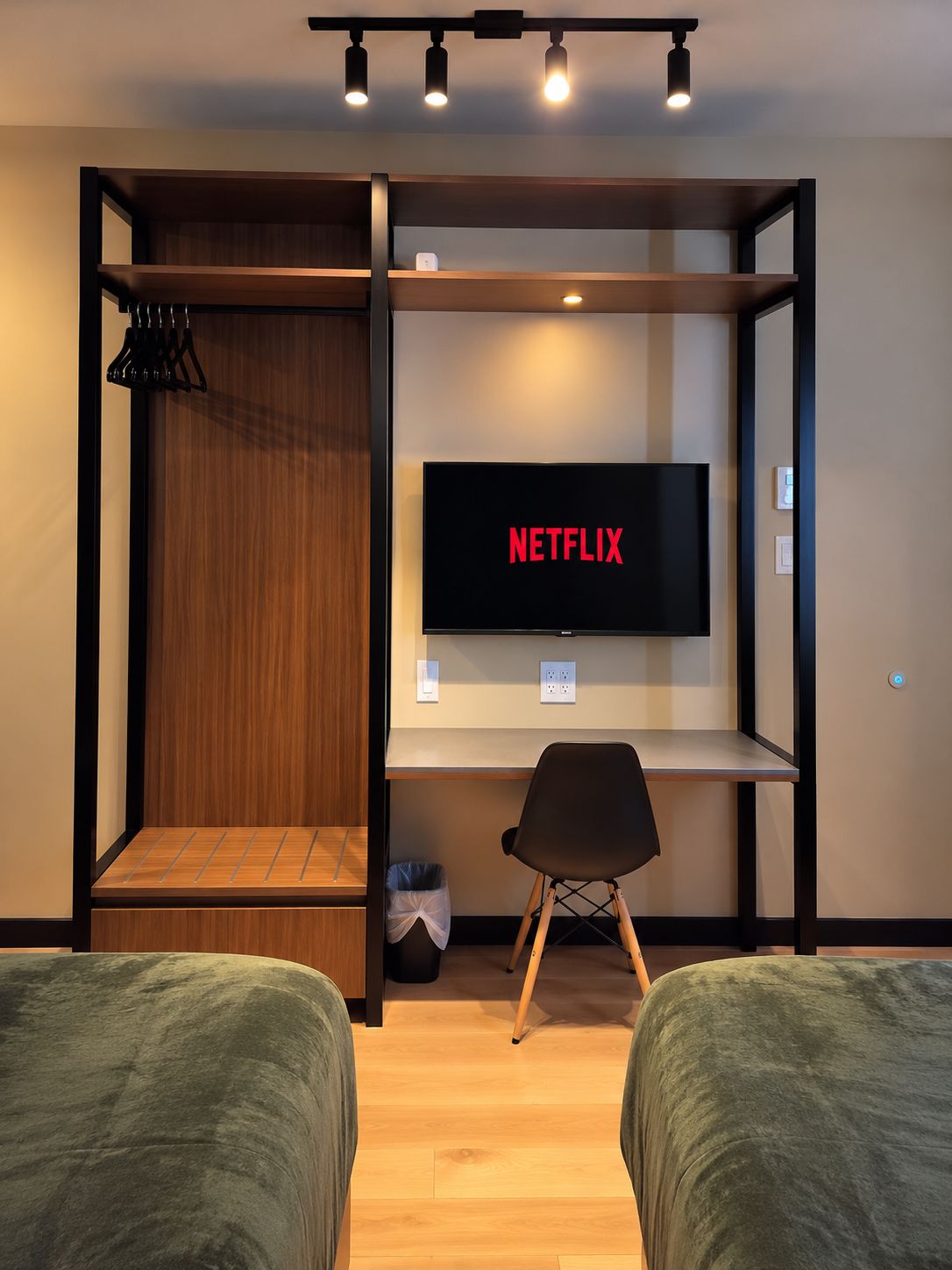 A room with a bed, a desk, a chair, a television, and a shelf.