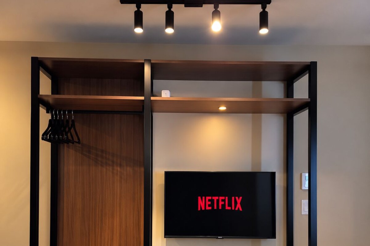 Una habitación con una cama, un escritorio, una silla, un televisor y una estantería.