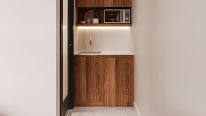 A narrow hallway with a built-in kitchen area featuring wooden cabinetry, a microwave, and a sink. - Motel du Lac Beauchamp (Gatineau)