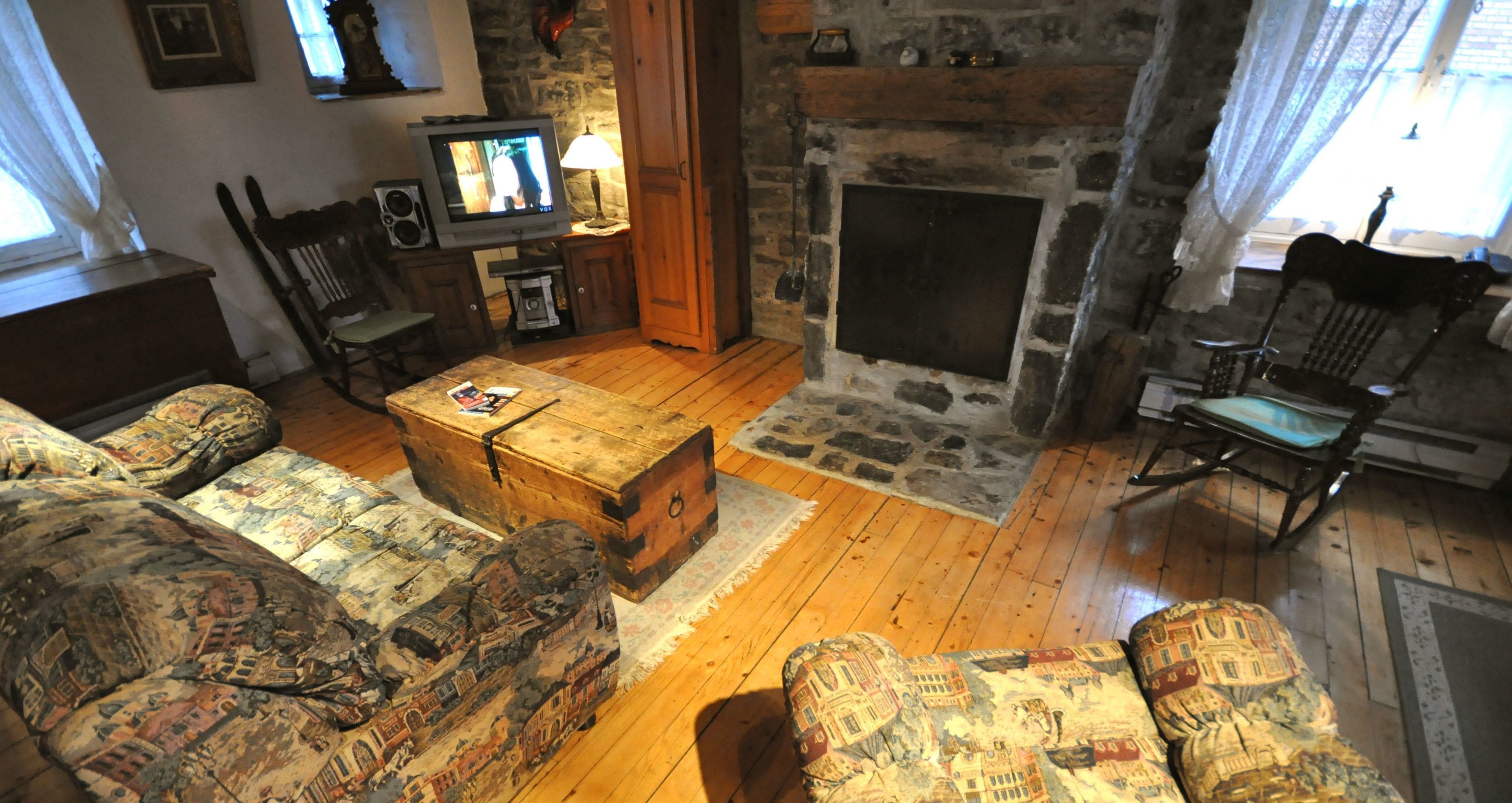 Un salon chaleureux avec une cheminée, un plancher en bois, des meubles à motifs et un téléviseur.