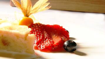 A dessert with a slice of cake, a strawberry, and a blueberry on a white plate.