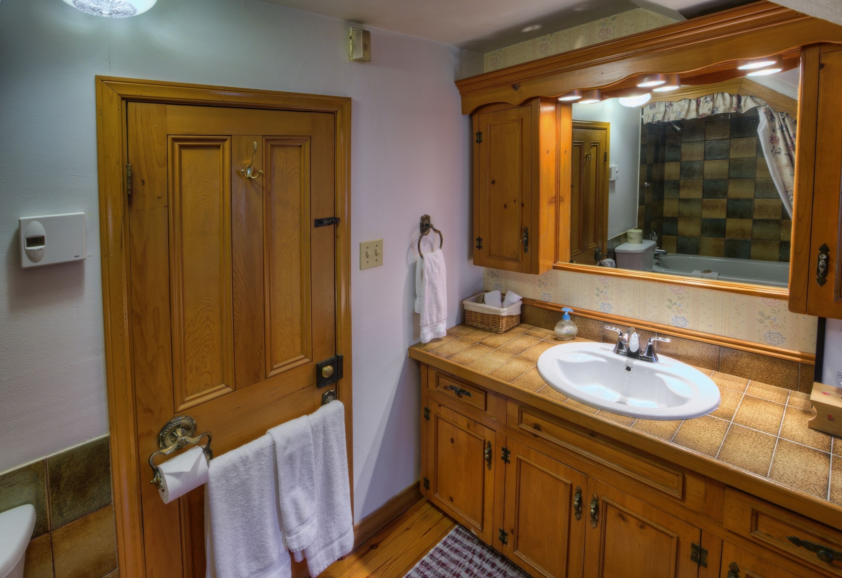 Ein Badezimmer mit Holzausstattung, einem Waschbecken, einem Spiegel und einer Toilette.