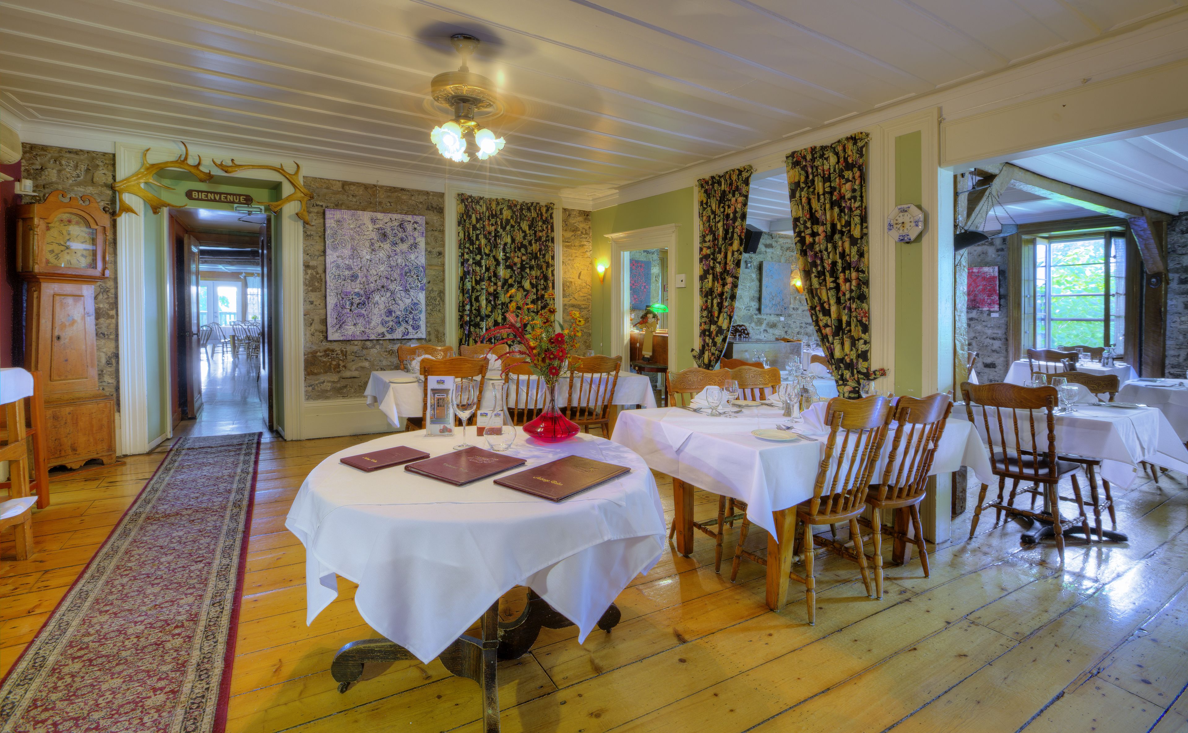 A dining area with round tables, wooden chairs, and a central floral arrangement.