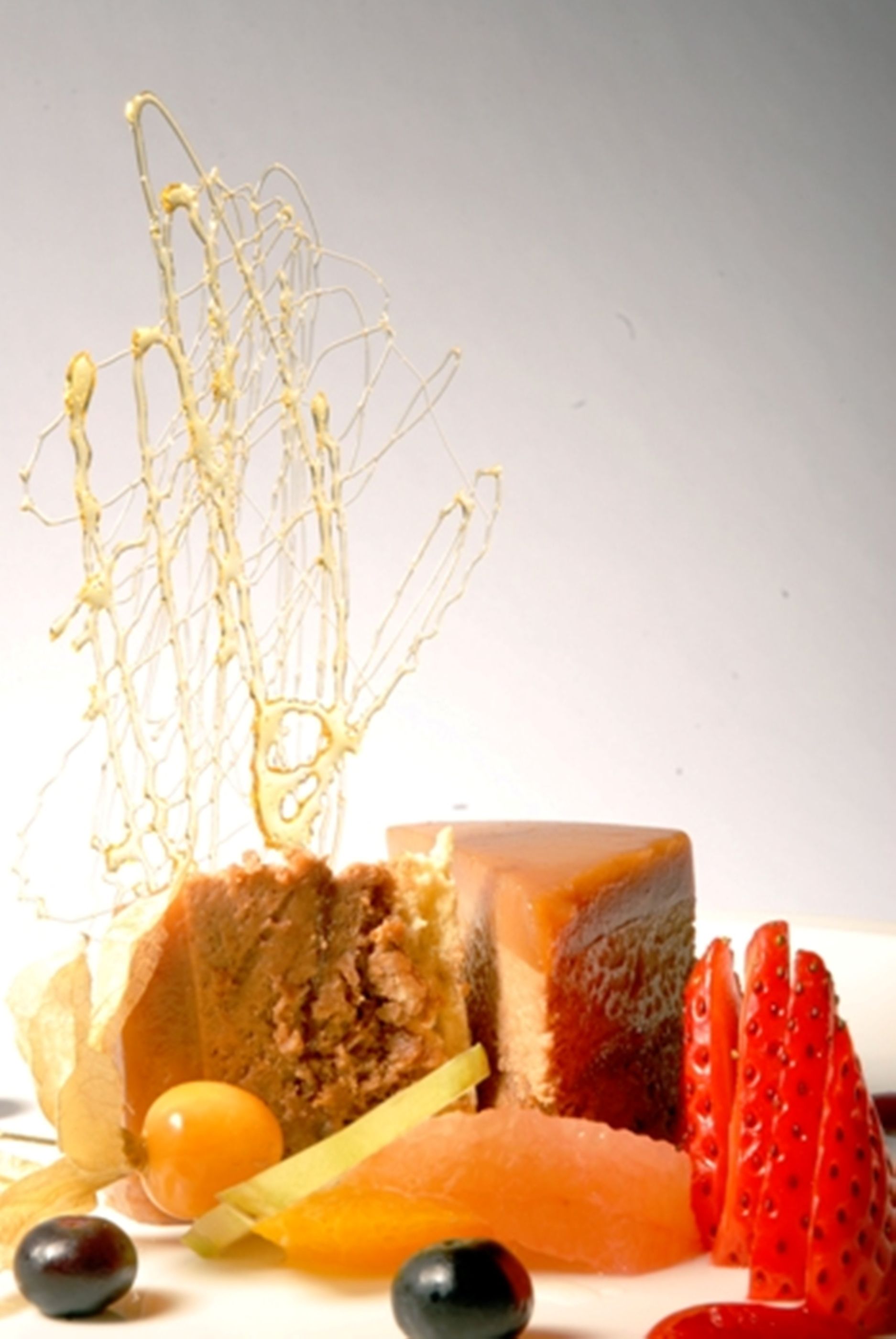 Un postre con una capa caramelizada, rodeado de fresas y uvas.
