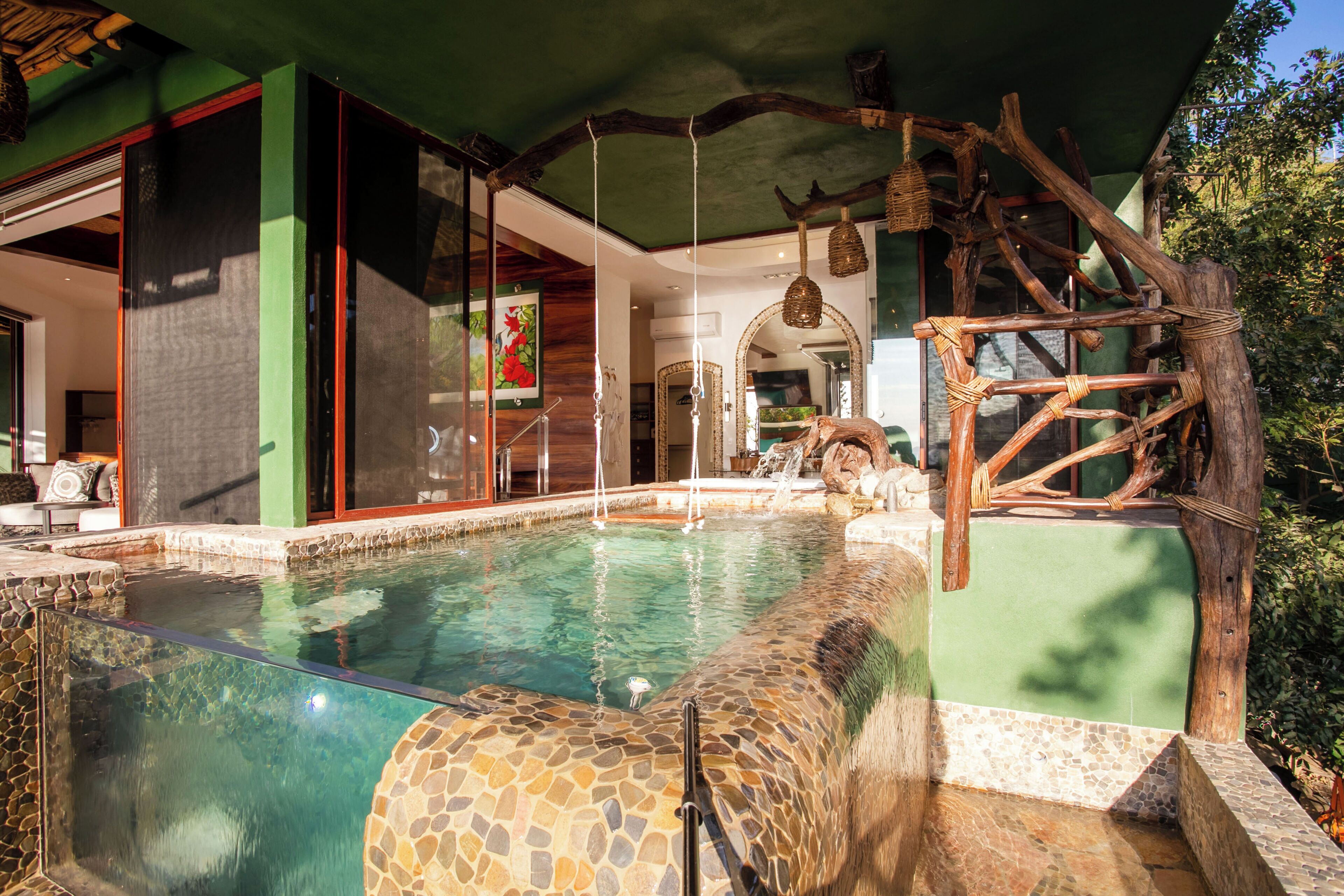 Una piscina con borde de piedra, cubierta de madera y una estructura de madera rústica.