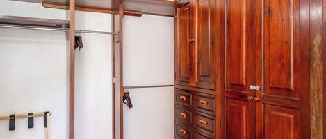 A room with a wooden wardrobe, a metal rack, and a wooden door.