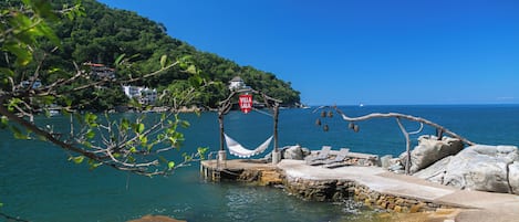 A coastal area with a hammock, a sign reading 'Villa Lala,' and a stone structure by the water.