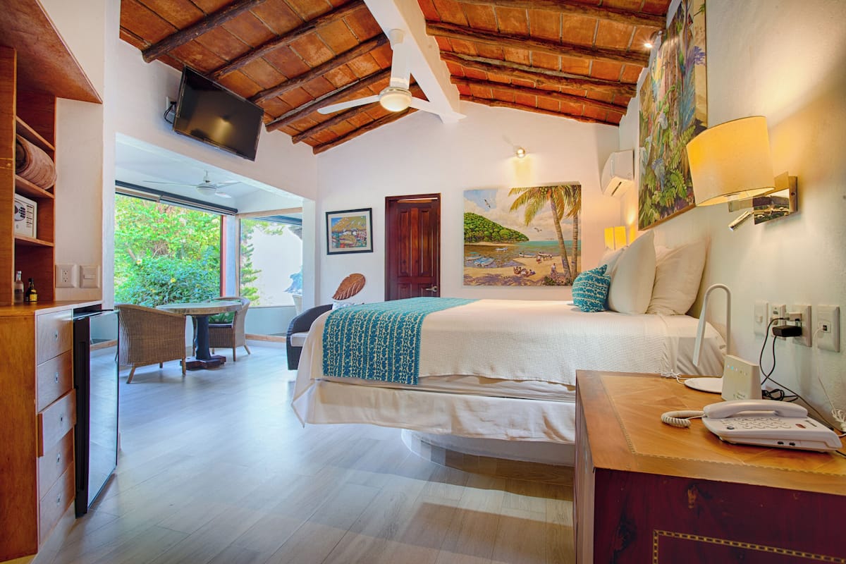 Una habitación de hotel con cama, escritorio, silla, televisor y un cuadro en la pared.