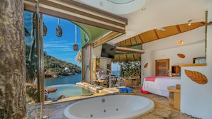 Un baño moderno con una bañera grande, zona de ducha con mampara de vidrio y vistas a un lago.
