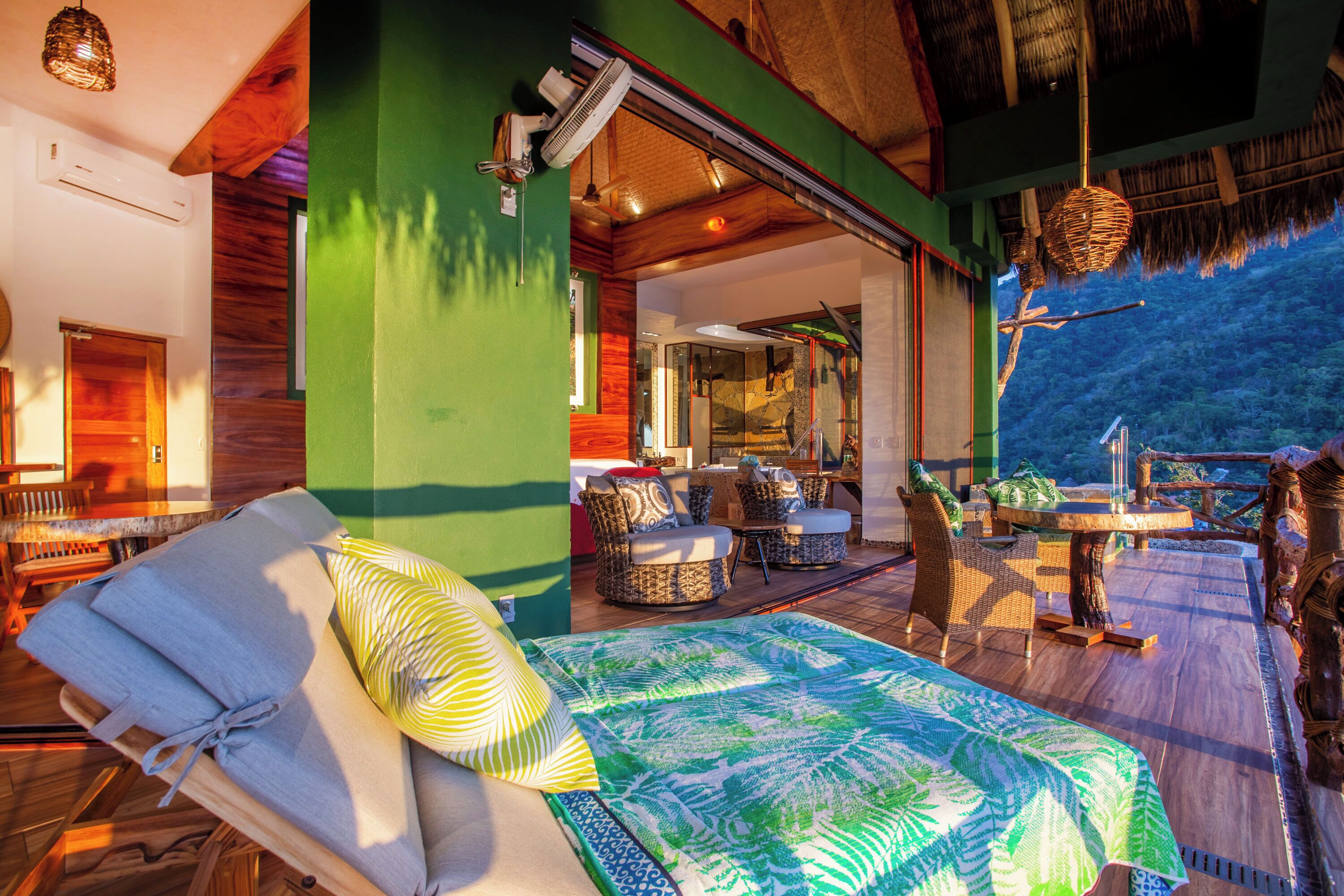 A room with a bed, wicker furniture, and a view of the outdoors.