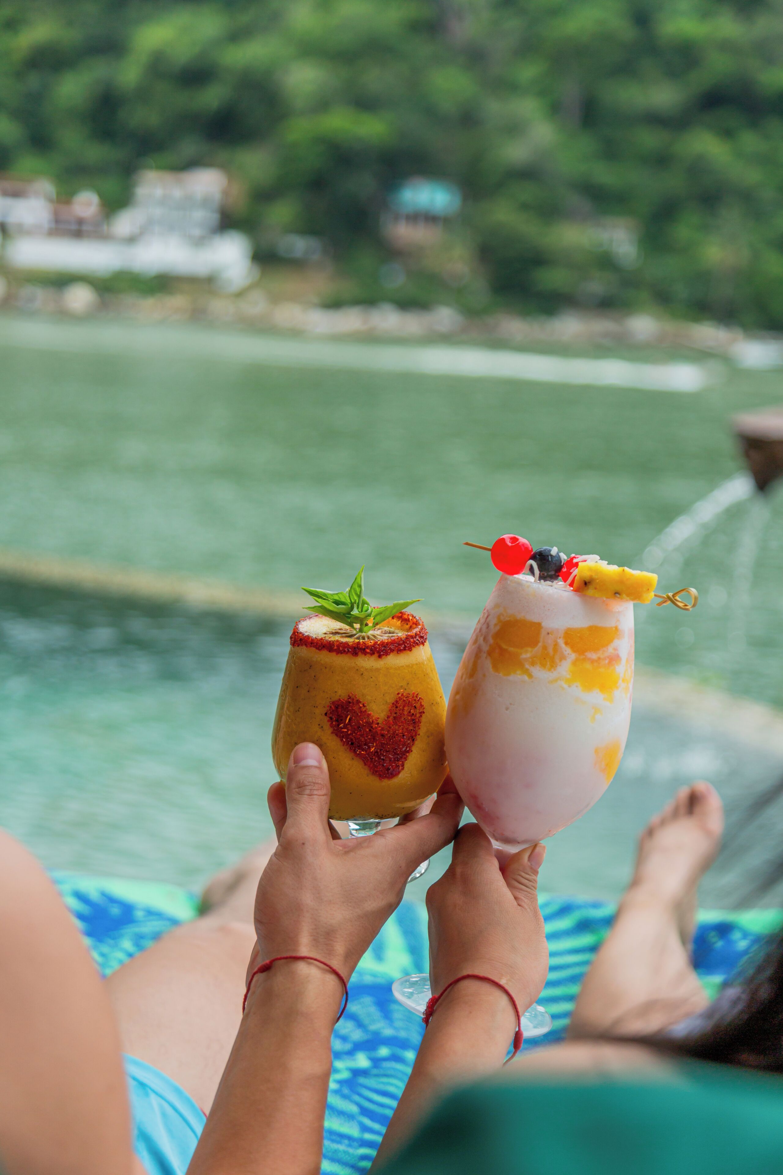 Twee drankjes met fruitdecoraties, vastgehouden door een persoon.