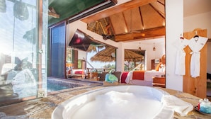 Un área de spa con un jacuzzi, techo de madera y vistas a un dormitorio con cama y televisor.