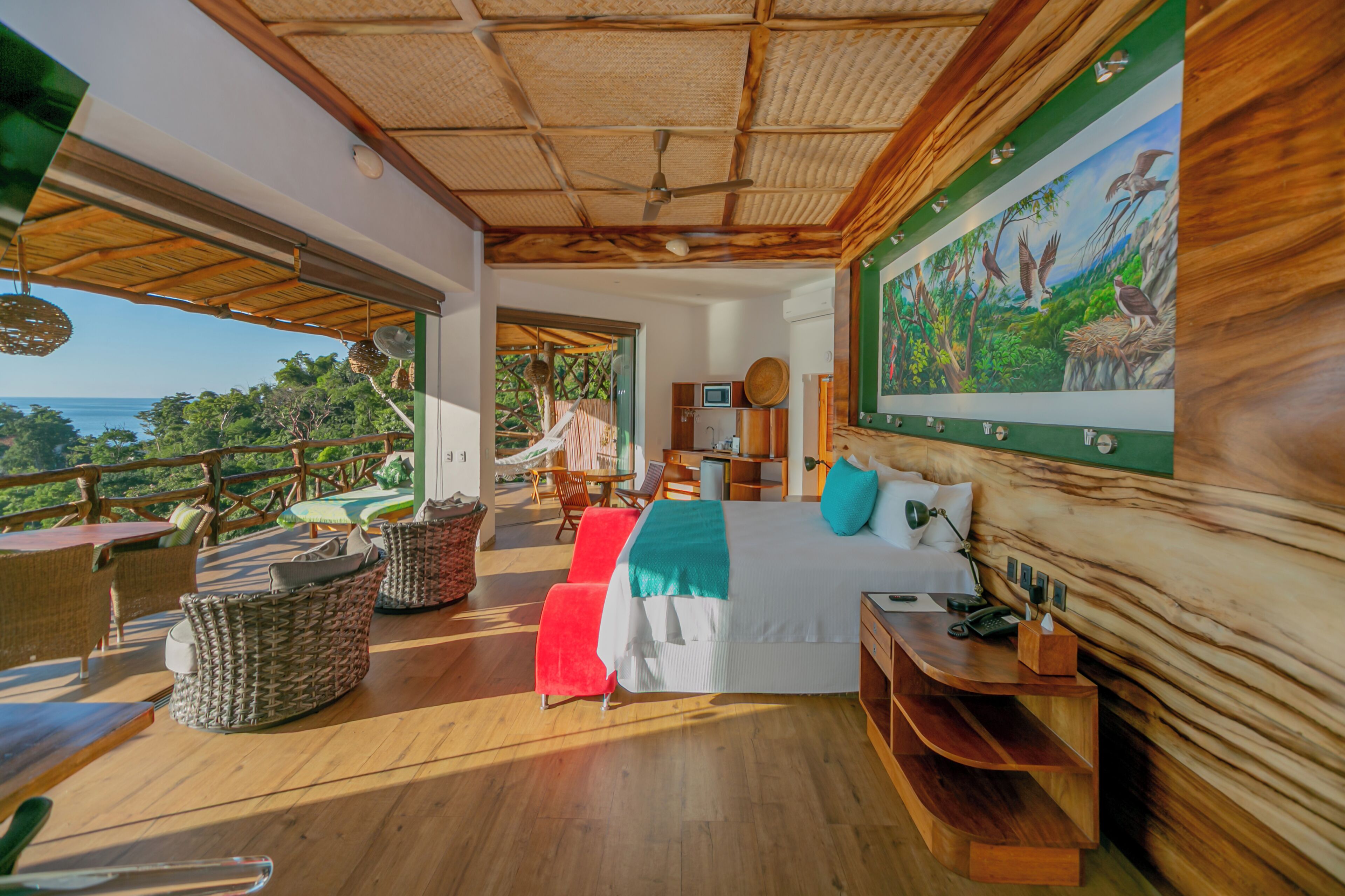 Ein Zimmer mit einem großen Bett, Holzmöbeln, einem Gemälde und Blick ins Freie.
