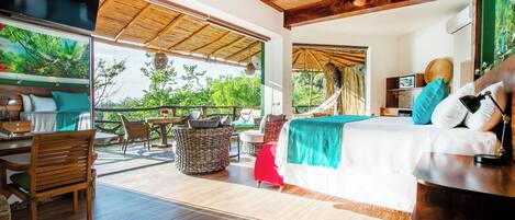 A spacious room with a bed, a desk, and a chair, a ceiling fan, and a view of greenery outside.