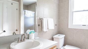 Een moderne badkamer met een wastafel, spiegel, toilet en raam.