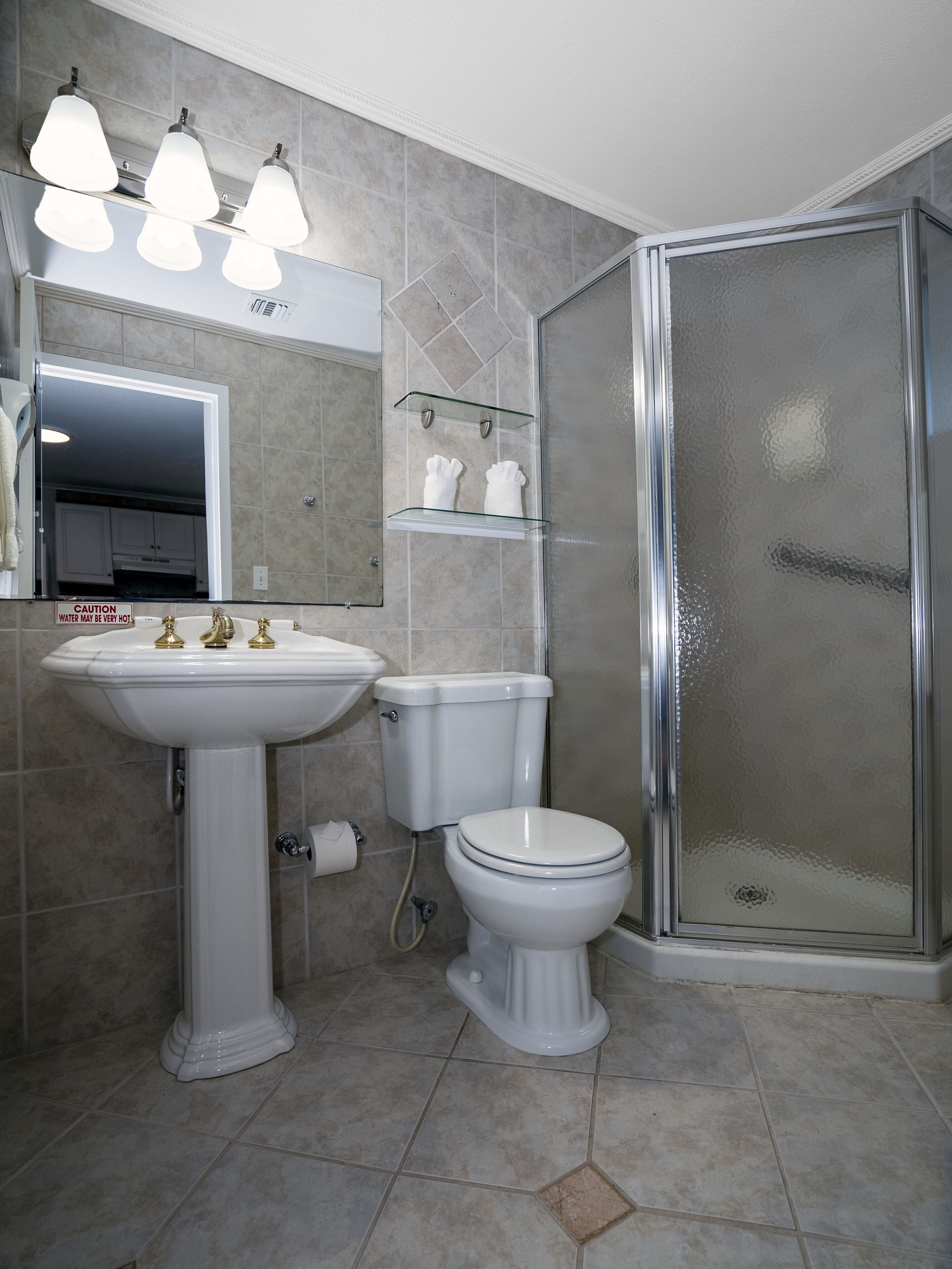 Une salle de bain avec un lavabo sur colonne, des toilettes et une douche à parois de verre.