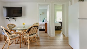 Un comedor con sillas de mimbre, una mesa de vidrio y un televisor de pantalla plana montado en la pared.