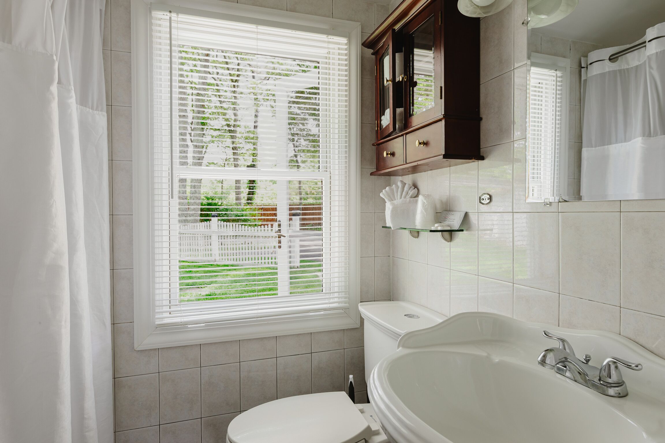 Ein Badezimmer mit Toilette, Badewanne, einem Fenster mit Jalousien und einem Schrank.