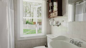 Ein Badezimmer mit Toilette, Badewanne, einem Fenster mit Jalousien und einem Schrank.