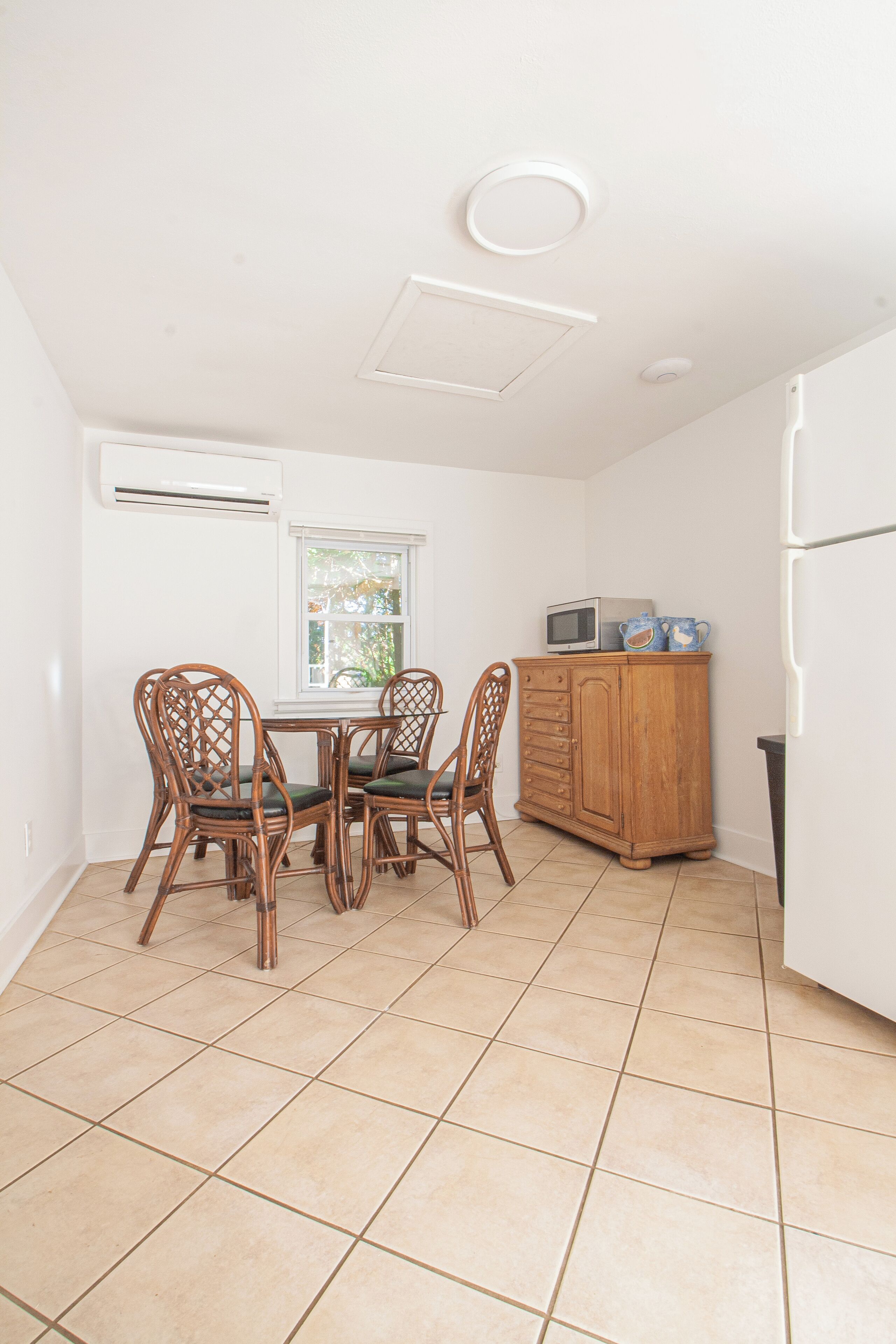 A compact kitchen with a dining table, chairs, a microwave, and a cabinet.