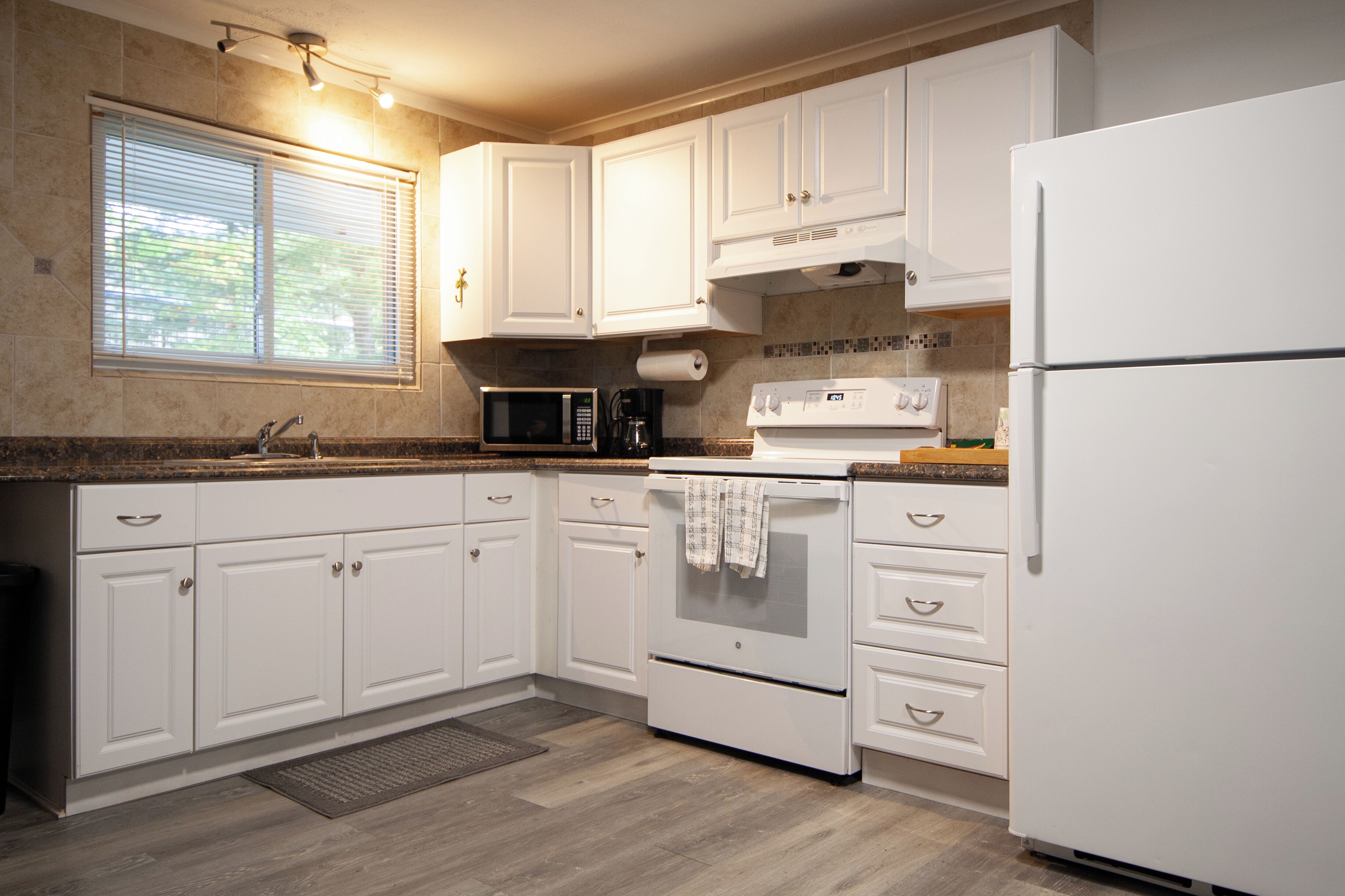 A kitchen with white cabinets, a microwave, a stove, and a refrigerator.