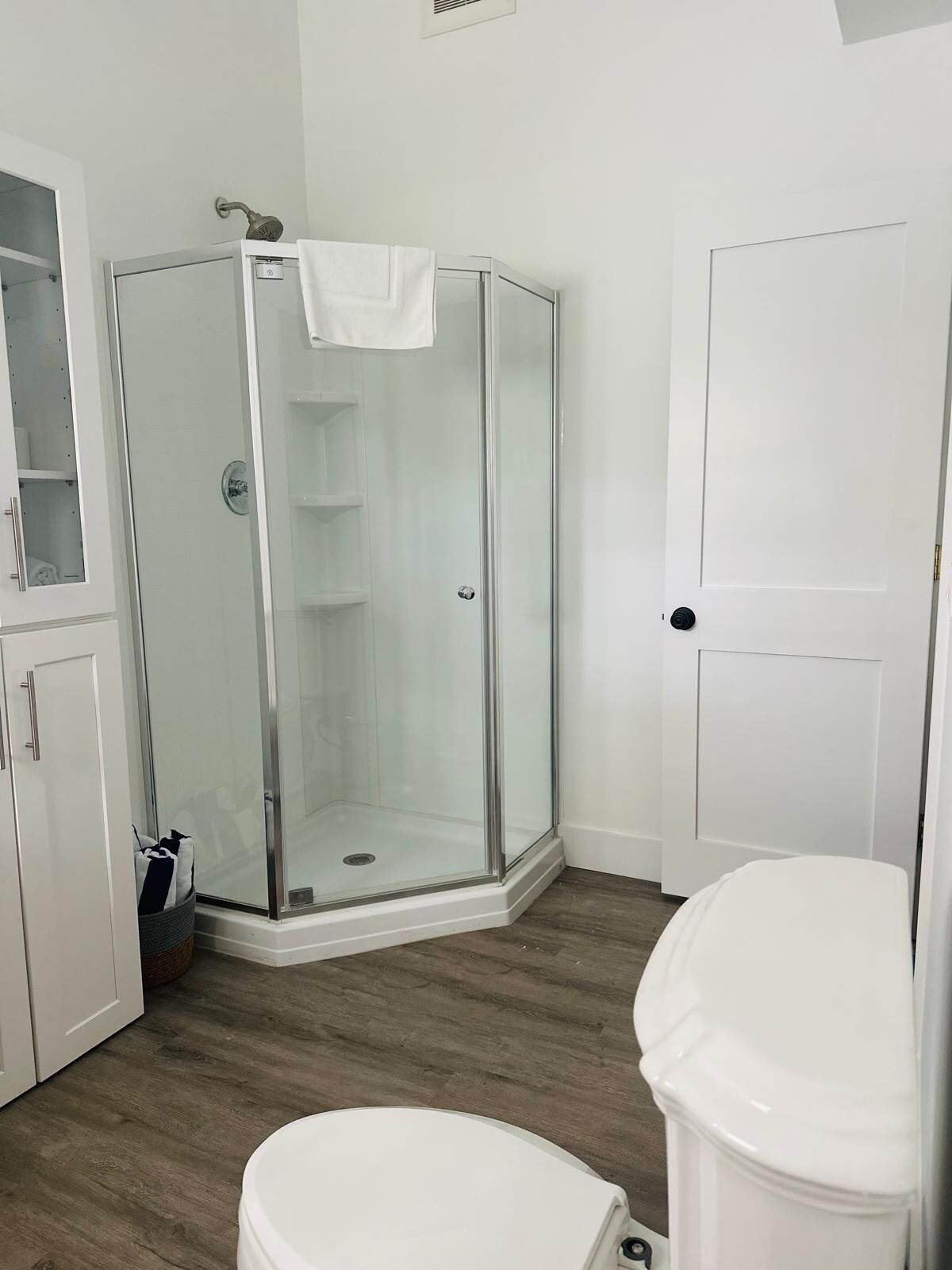 Un baño con cabina de ducha de vidrio, un inodoro y un armario.