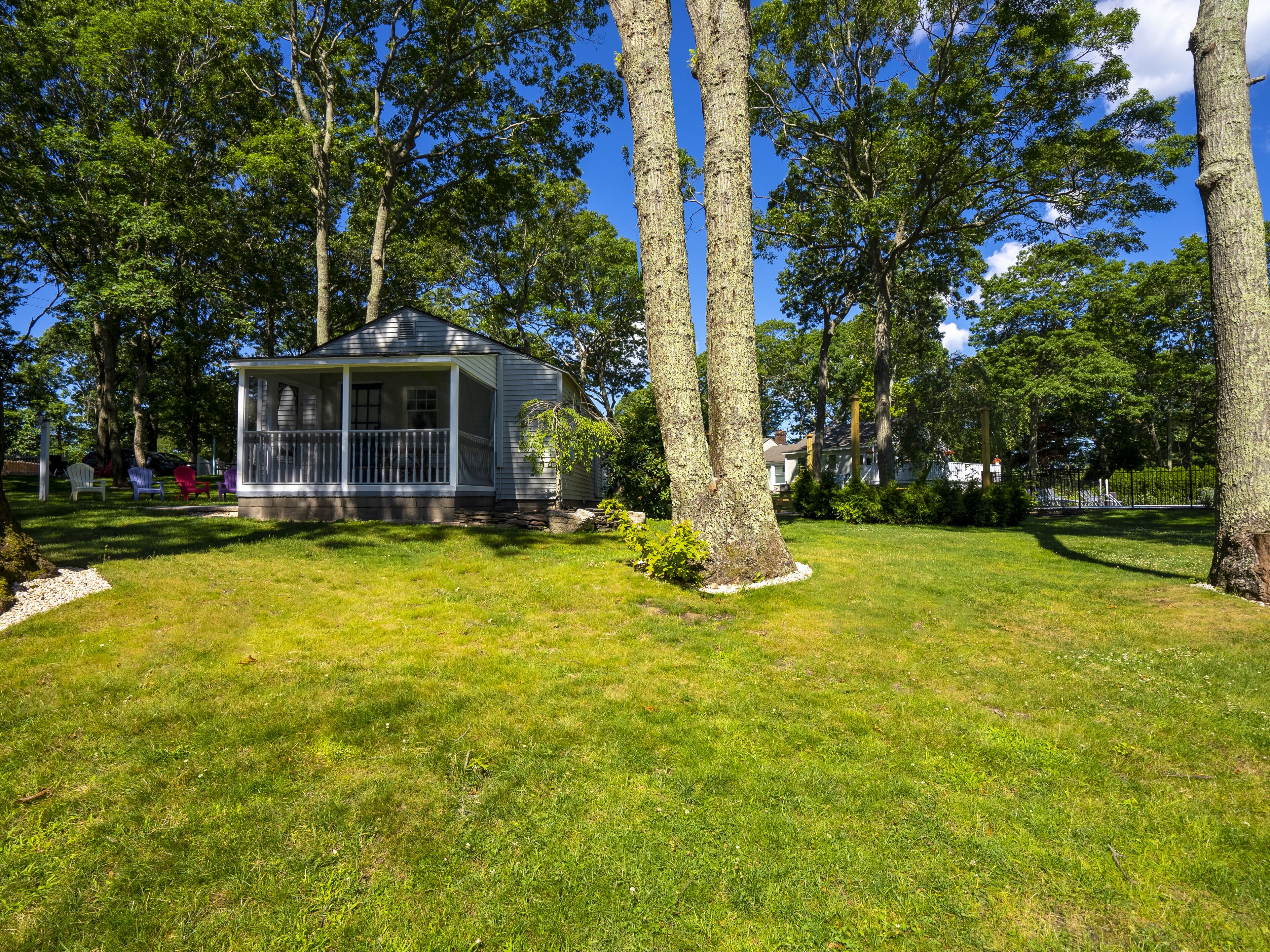 A gazebo with a covered porch, surrounded by a well-maintained lawn and tall trees.