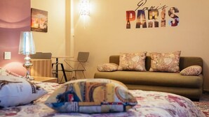 A cozy room with a bed, a sofa, a lamp, and a wall with 'Paris' written on it. - Porto Bello Design Hotel (Nafplio)