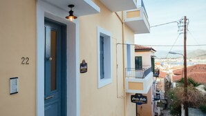 A building with a blue door, a sign reading "Porto Bello Guest House", and a view of the street and buildings in the background. - Porto Bello Design Hotel (Nafplio)