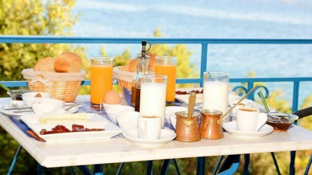 A breakfast setup with bread, eggs, and beverages on a table with a scenic view. - Porto Bello Design Hotel (Nafplio)