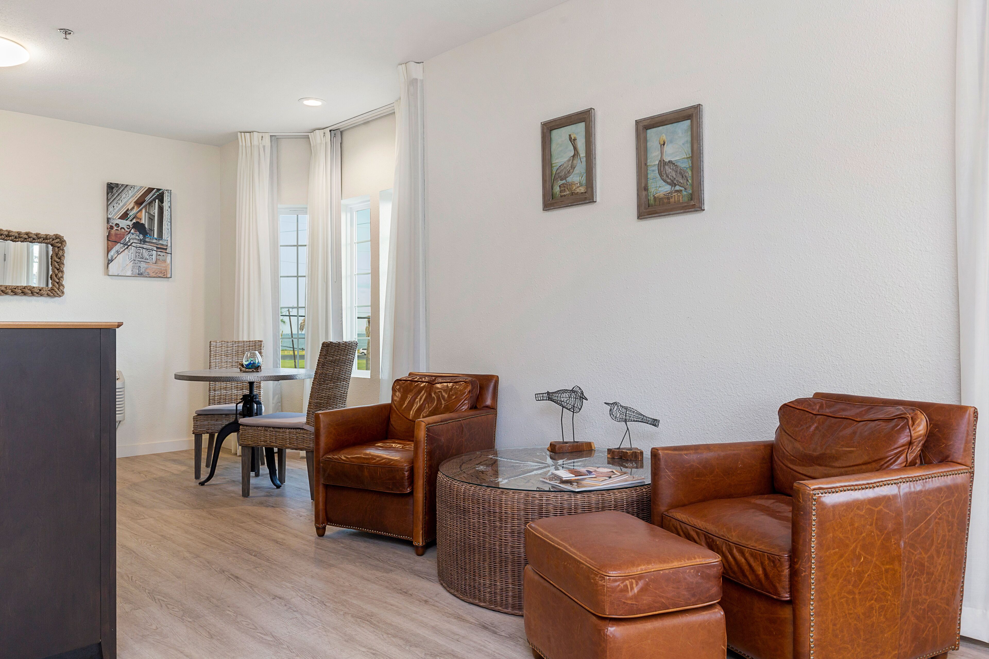 Ein Wohnzimmer mit Ledermöbeln, einem Glastisch und Kunstwerken an den Wänden.