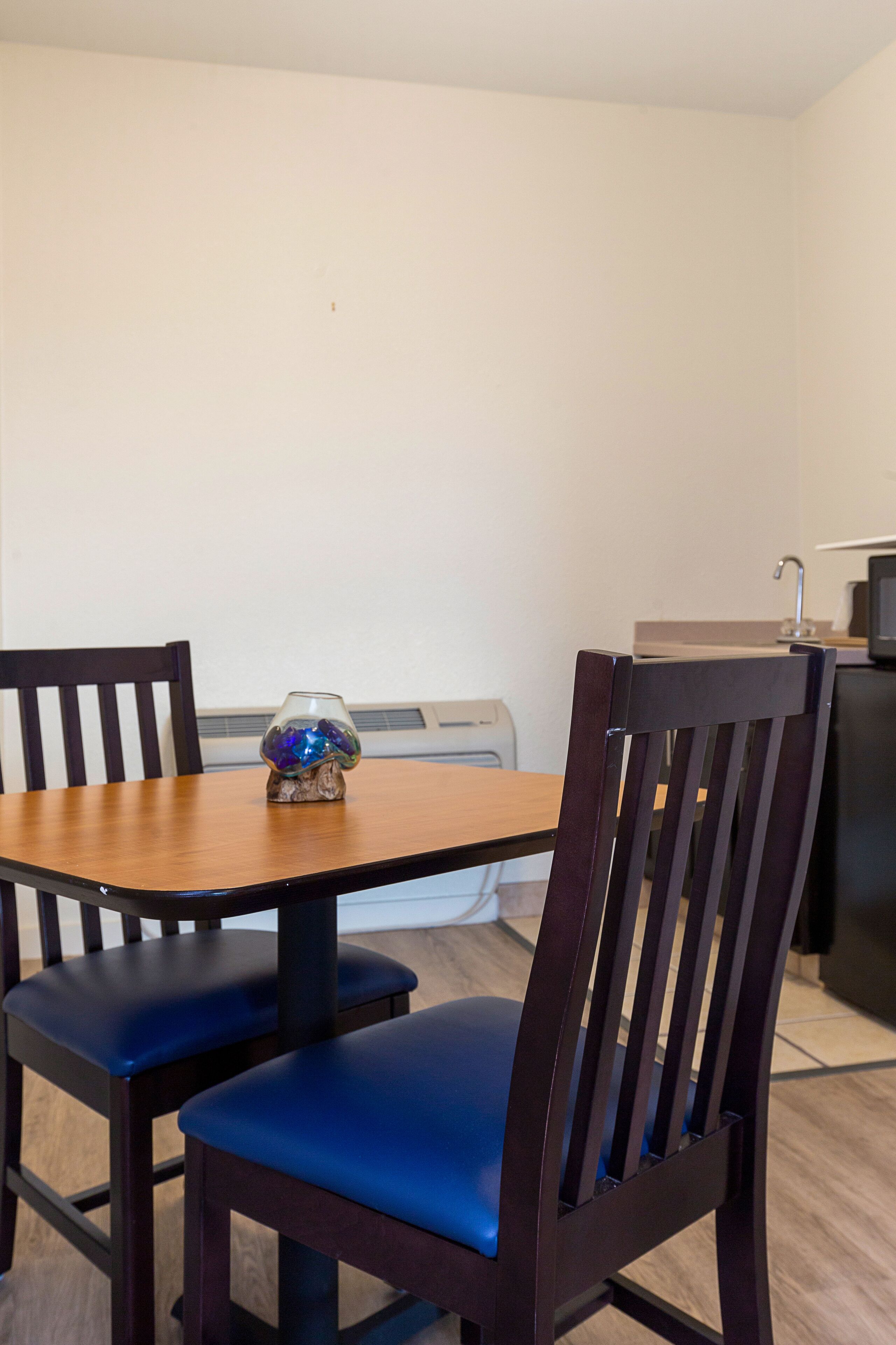 Un coin repas avec une table en bois et deux chaises rembourrées.