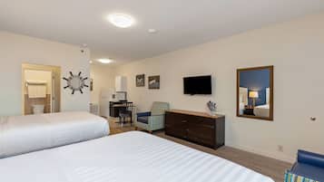 Ett hotellrum med två sängar, ett skrivbord, en byrå, en stol, en TV och en spegel.