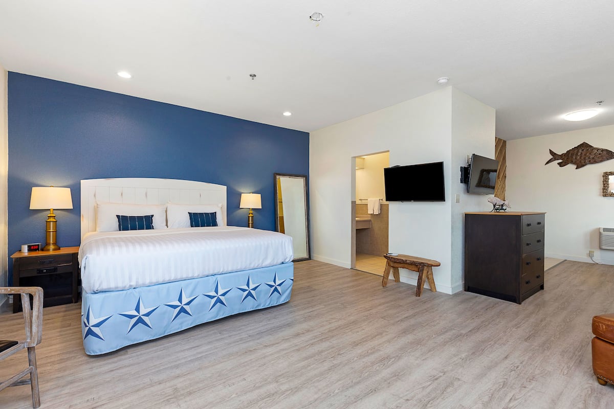 A bedroom with a bed, bedside tables, a TV, and a dresser.