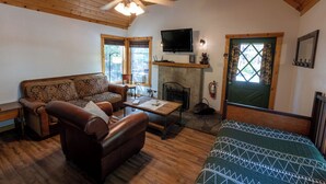Un salon chaleureux avec un plafond en bois, une cheminée, un téléviseur et un lit.