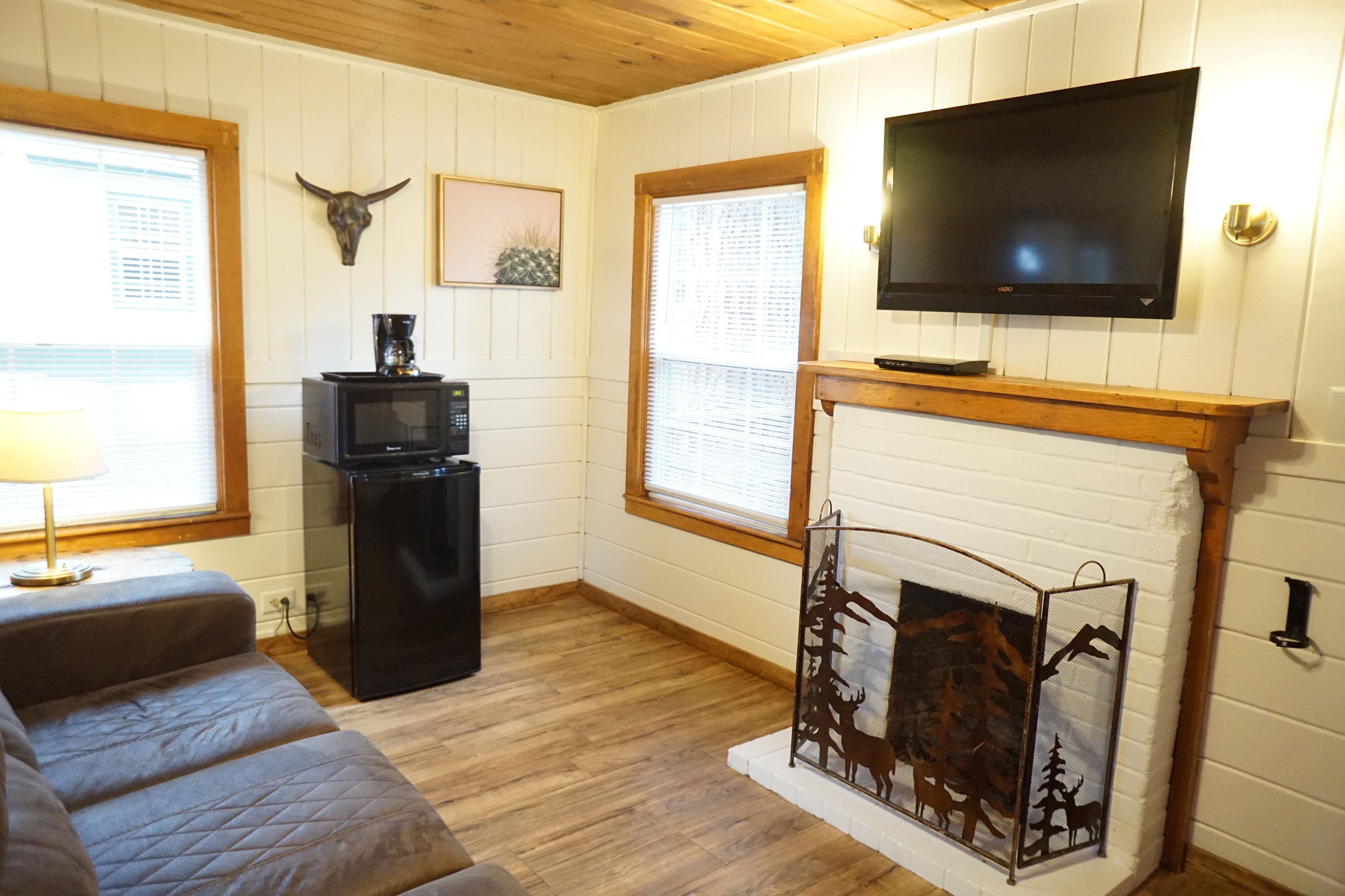 Una sala de estar acogedora con chimenea, televisor de pantalla plana, sofá y un separador decorativo de metal.