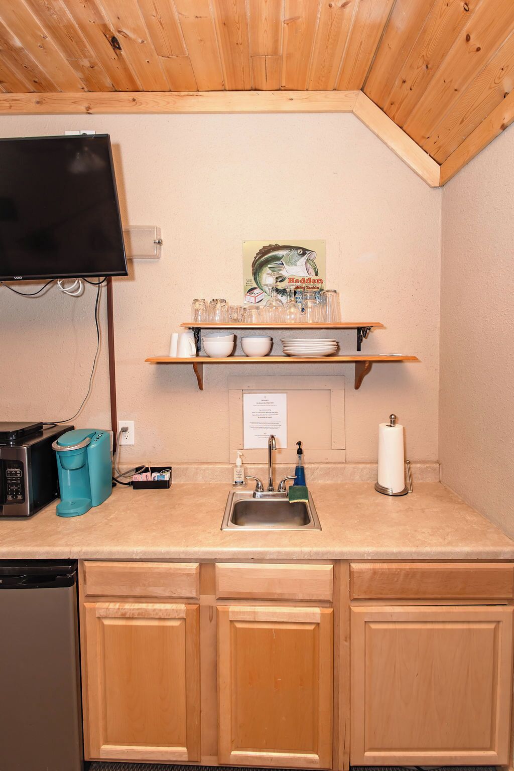 A compact kitchen with a wooden countertop, a sink, a microwave, and a coffee maker.