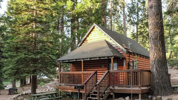 Une cabane en rondins avec une terrasse en bois, un escalier et une table de pique-nique.